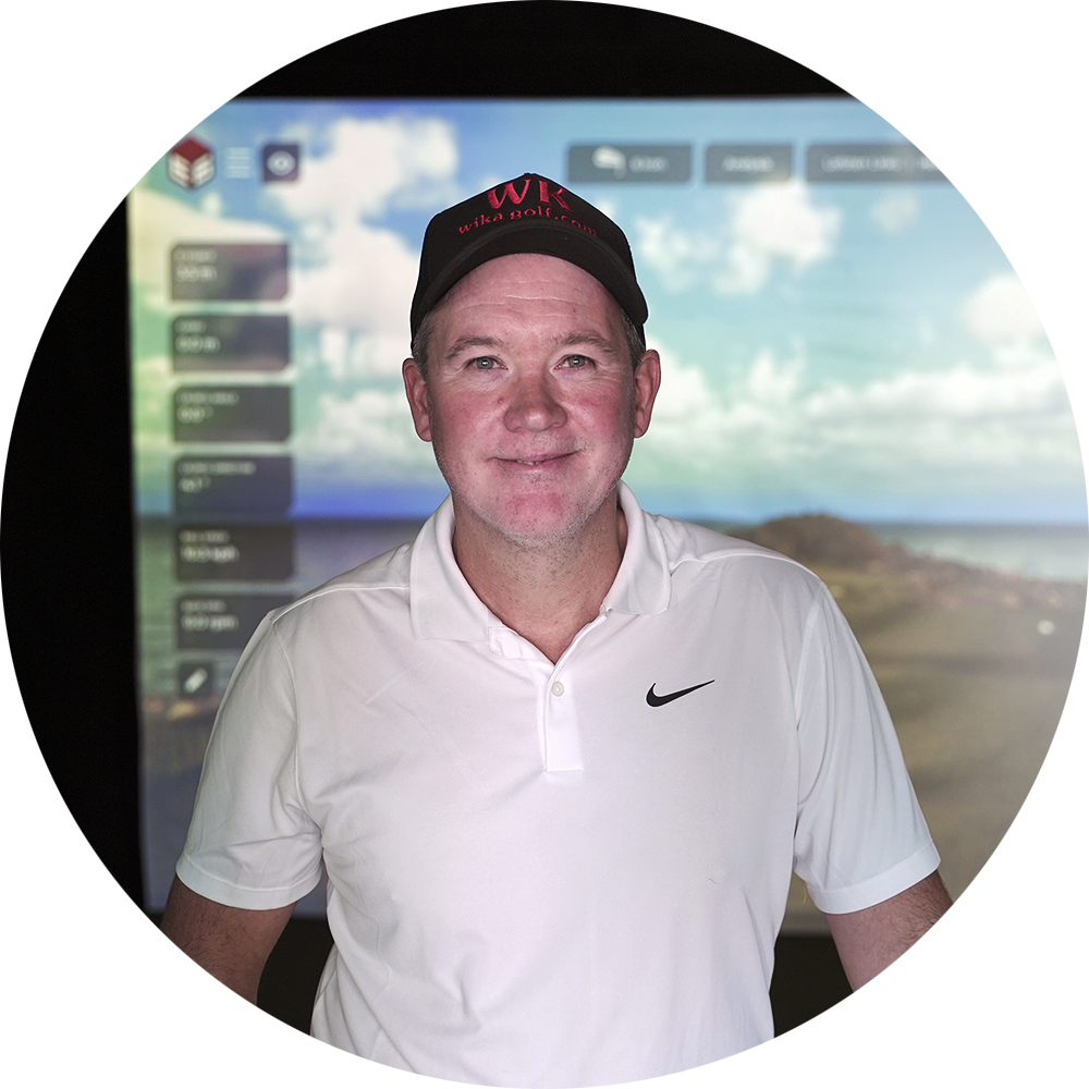 Man med vit pikétröja och svart keps med texten "Wika Golf" står framför en golfsimulator med landskapsbakgrund.