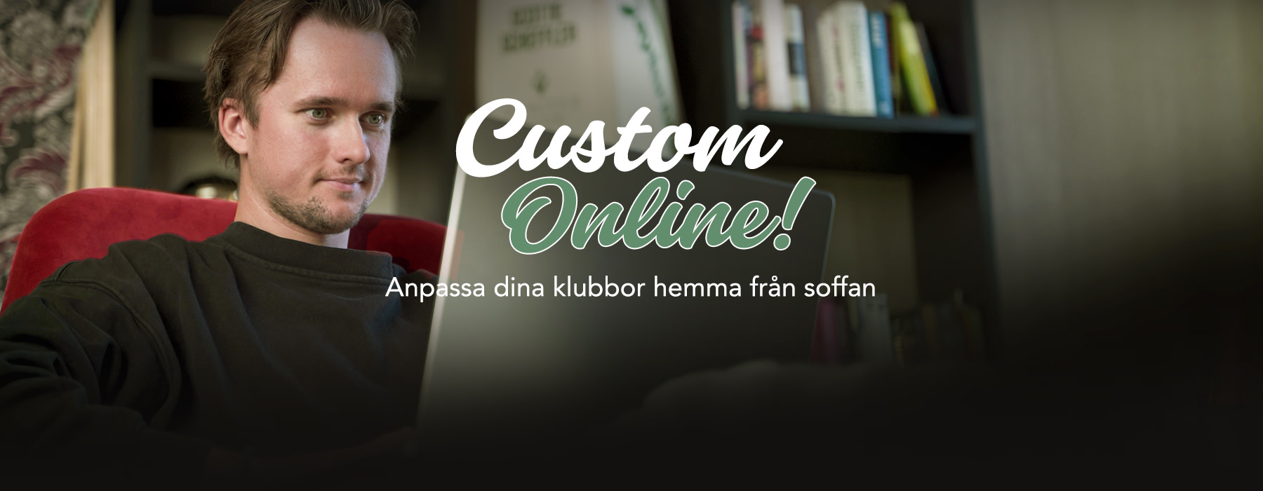 Man sitter i en röd stol och arbetar på en bärbar dator med texten "Custom Online!" över skärmen, bokhylla i bakgrunden.